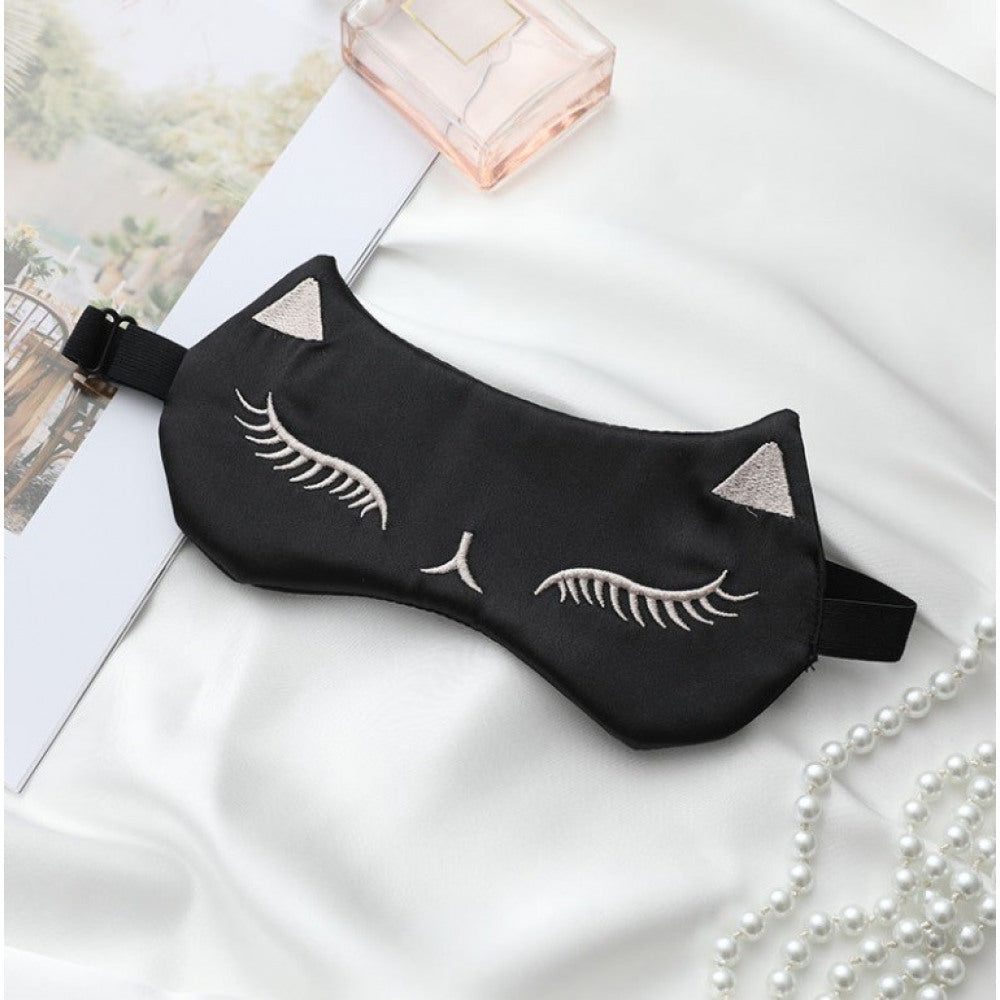 Schwarze Schlafmaske im Katzen-Design mit gestickten geschlossenen Augen und Ohren auf weissen Hintergrund.