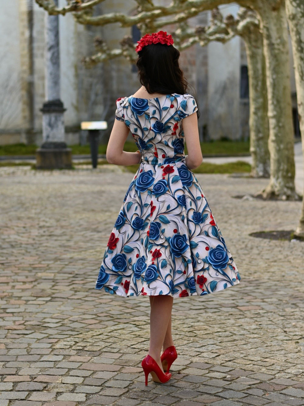Eine Frau trägt das Elowen Floral Swing Dress, Ganzkörperansicht im Stehen, Ansicht von hinten.