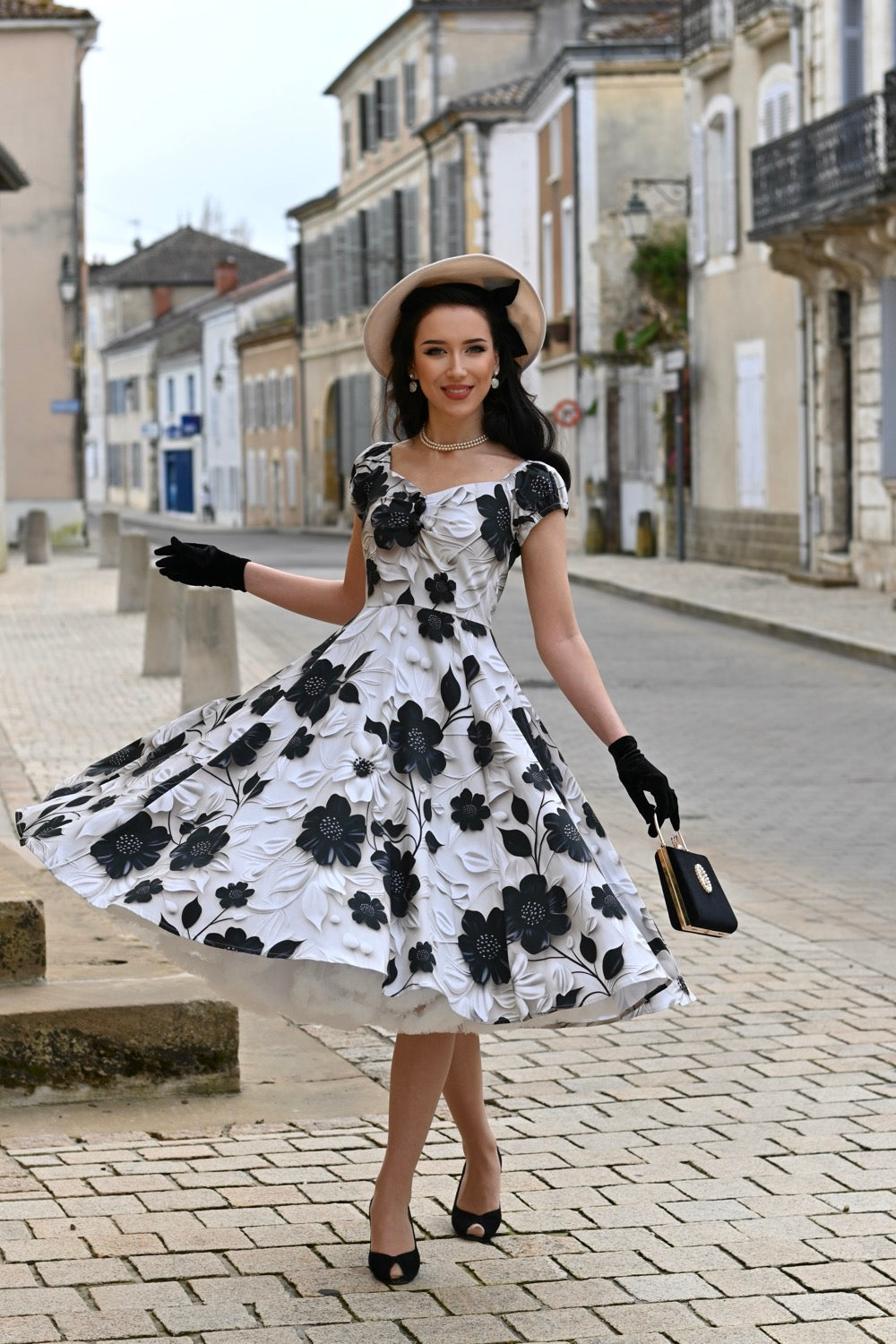 Eine Frau trägt das Taylor Floral Swing Dress, Ganzkörperansicht im Stehen. Fokus auf den schwingendem Rock