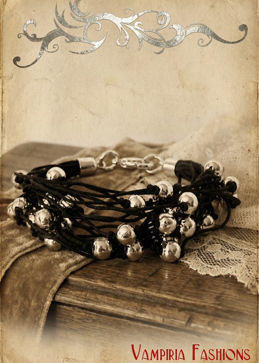 Schwarzes mehrreihiges Armkettchen im Gothic-Stil mit silbernen Kugelperlen auf Vintage-Untergrund mit Stoff und Holzoptik.