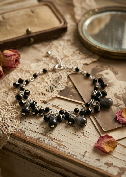 Filigranes Gothic Perlen Armkettchen mit schwarzen Perlen und tropfenförmigen Anhängern auf einer Vintage-Holzoberfläche mit Spitze dekoriert.