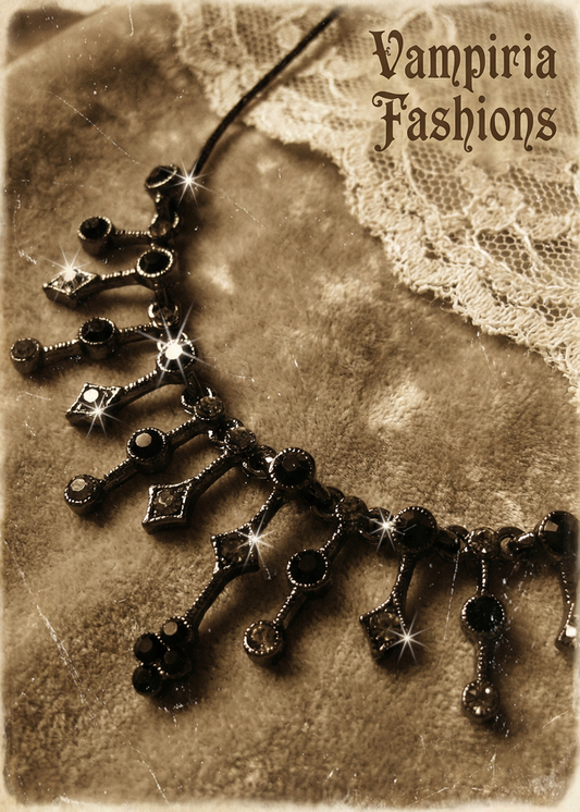 Detailaufnahme eines schwarzen Gothic-Colliers mit funkelnden Strasssteinen und ornamentalem Anhängerbereich auf samtigem Stoff.