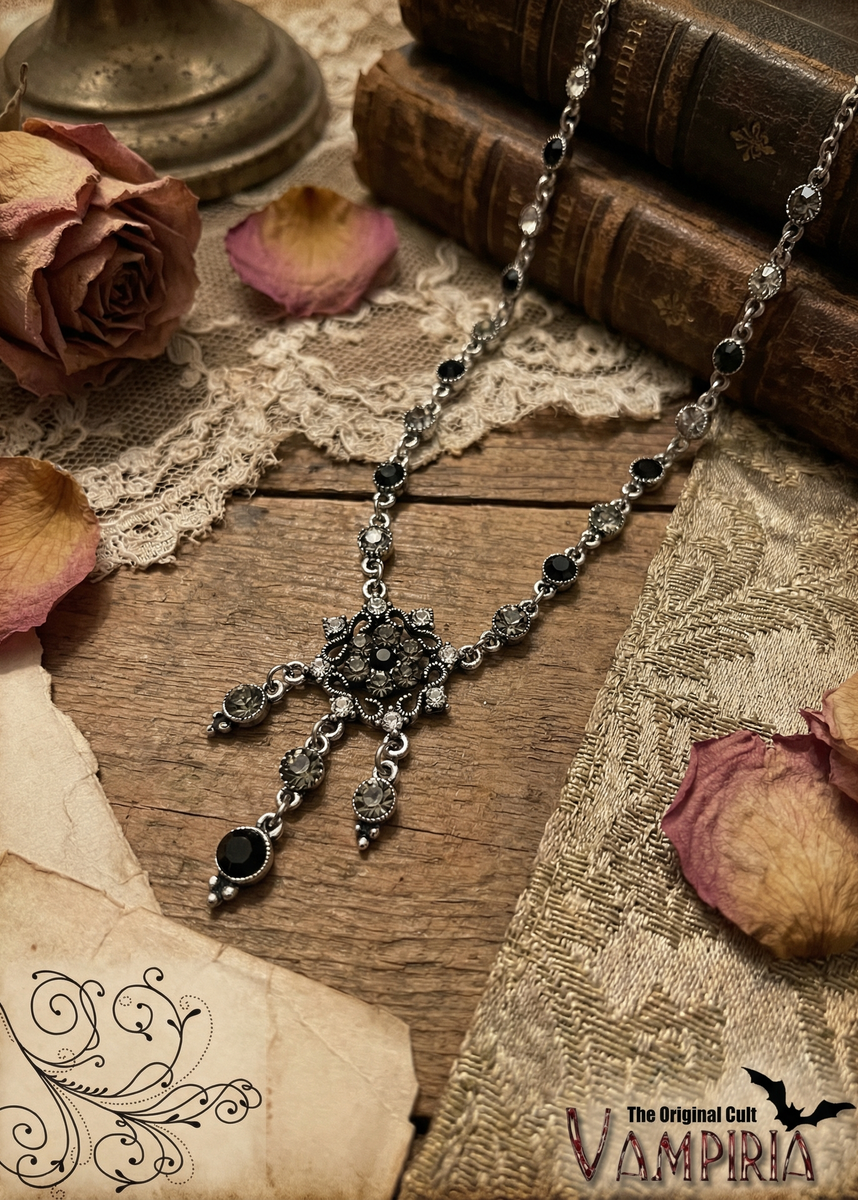 Gothic Halskette mit ornamentalem Mittelteil und hängenden Elementen auf Holztisch mit Vintage-Dekoration.