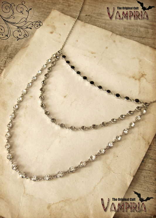 Dreireihiges Collier mit klaren und schwarzen Kristallsteinen auf hellem Papierhintergrund in Vintage-Inszenierung.