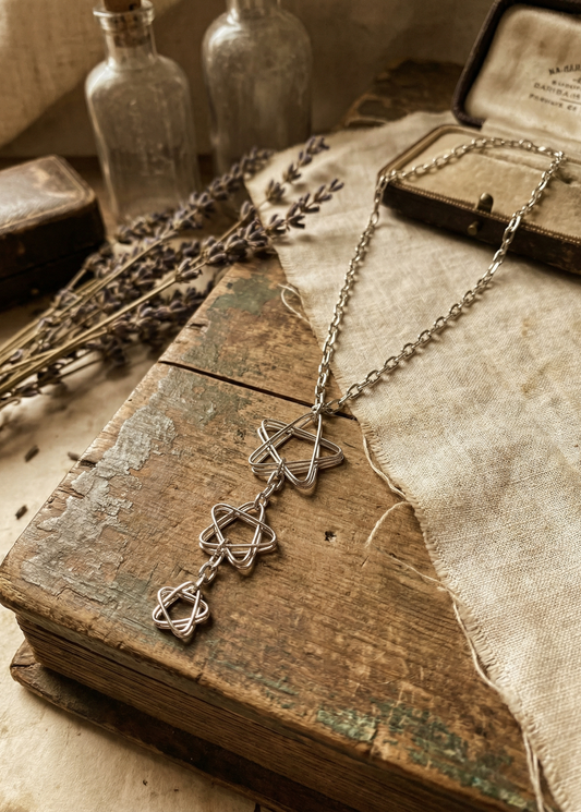Drei-Sterne Collier an feiner Kette auf altem Buch dekoriert, Vintage-Arrangement mit Lavendel.