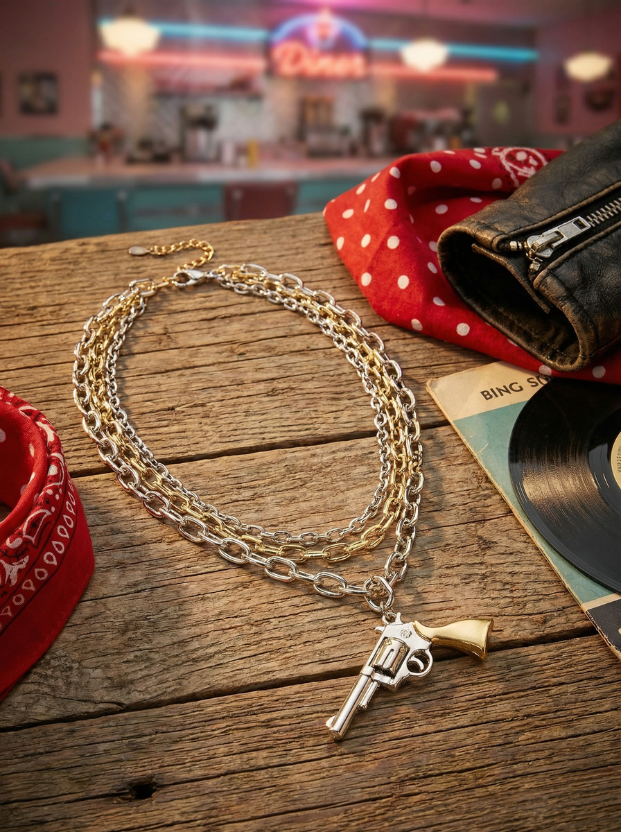 Rockabilly-Kette mit Revolver-Anhänger auf Holztisch neben Schallplatte, Bandana und Lederjacke im Retro-Stil.