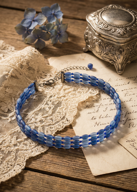 Blaues mehrreihiges Choker-Halsband aus ovalen Perlen auf Spitze und Papier im Vintage-Setting.