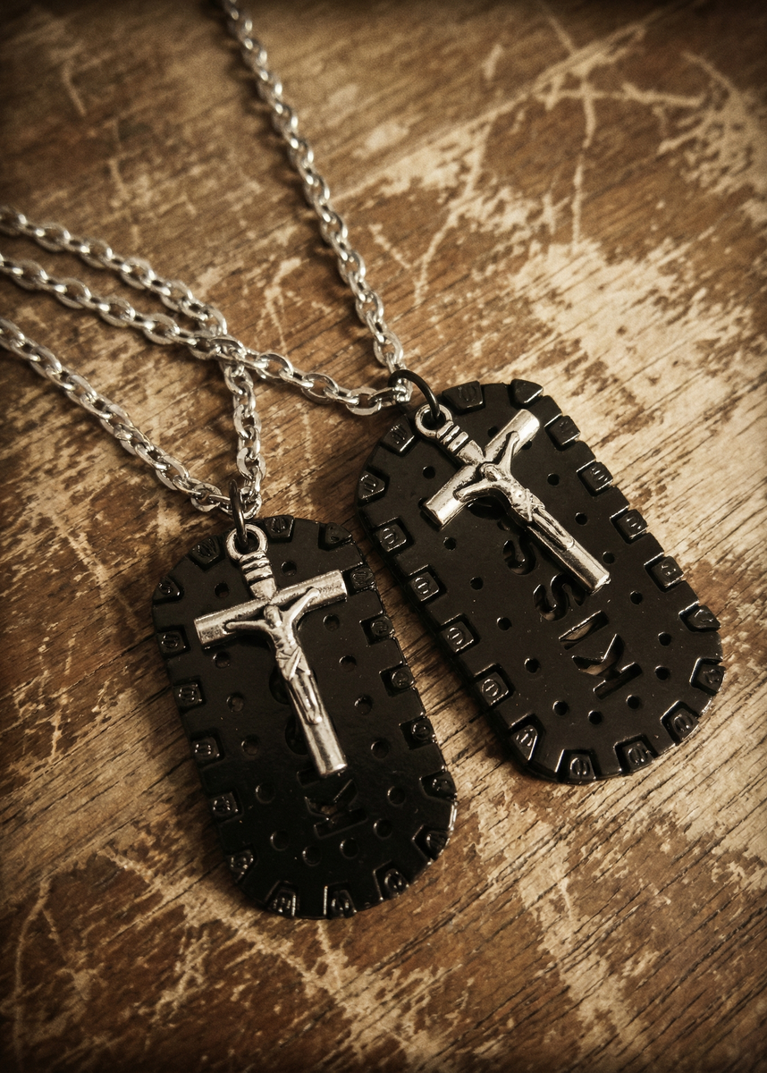 Zwei schwarze Plaketten-Anhänger mit silberfarbenem Kreuz und silberfarbenen Ketten auf einer Holzoberfläche.