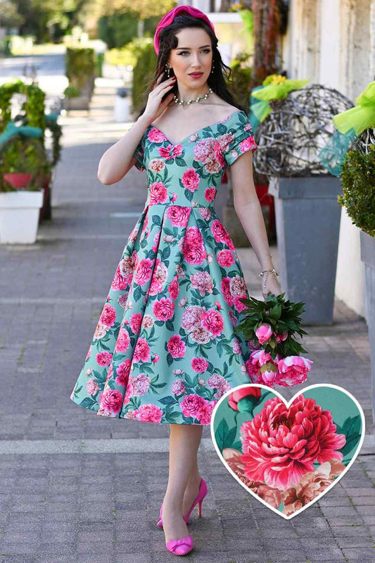 Frau trägt mintfarbenes Off-Shoulder Kleid mit rosa Pfingstrosen-Print und schwingendem Rock im 50er-Jahre-Stil.