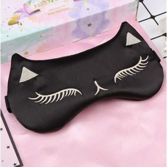 Schwarze Schlafmaske im Katzen-Design mit gestickten geschlossenen Augen und Ohren auf rosa Hintergrund.