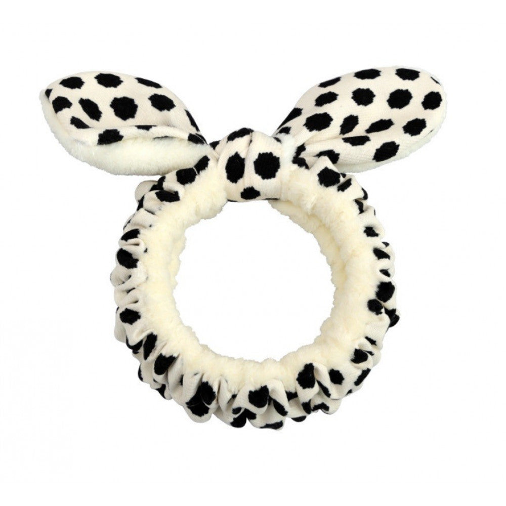 Flauschiger Kosmetik-Haarreif in Weiß mit schwarzen Leo-Flecken und Schleifen-Detail auf hellem Hintergrund.