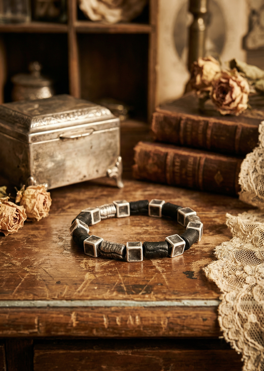 Schwarzes Armband mit runden und eckigen Perlen in Steinoptik auf Holztisch im Vintage-Setting