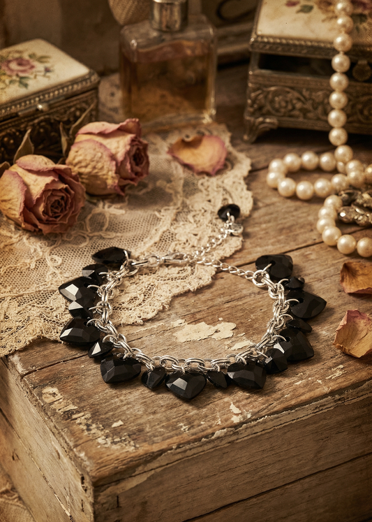 Vintage Gothic Armband mit schwarzen facettierten Herzanhängern auf Holzuntergrund.