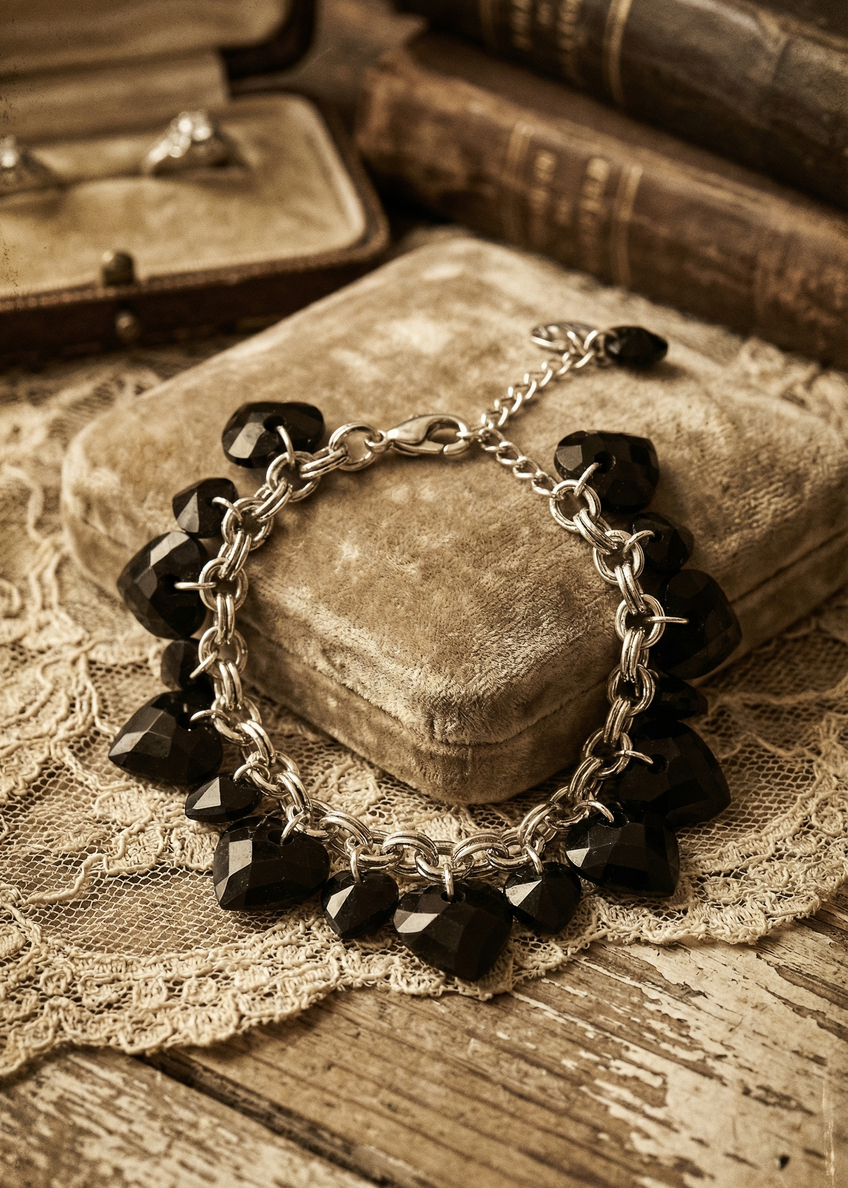 Schwarzes Armband mit Herzanhängern aus Steinoptik auf Schmuckbox im Vintage-Stil.