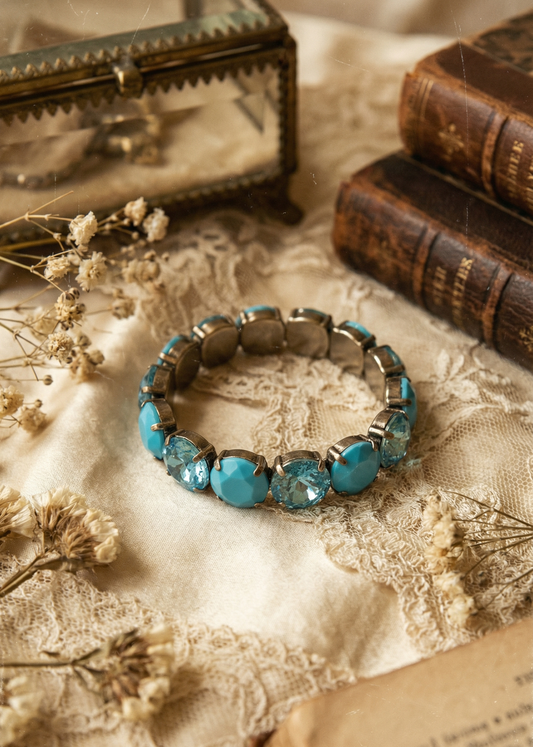 Türkisfarbenes Armband mit facettierten Steinen auf rustikalem Holztisch im Vintage-Setting.