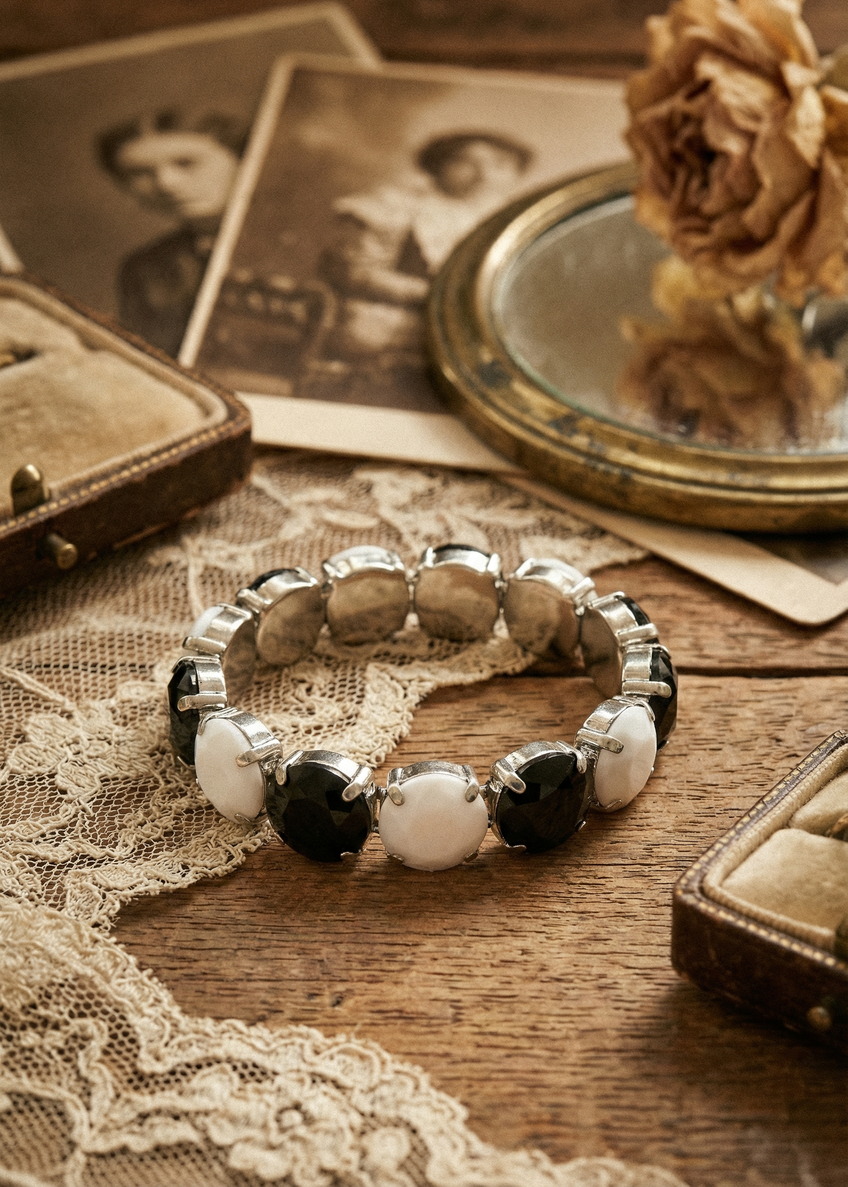 Vintage Armband mit schwarz-weißen Schmucksteinen auf dekoriertem Untergrund