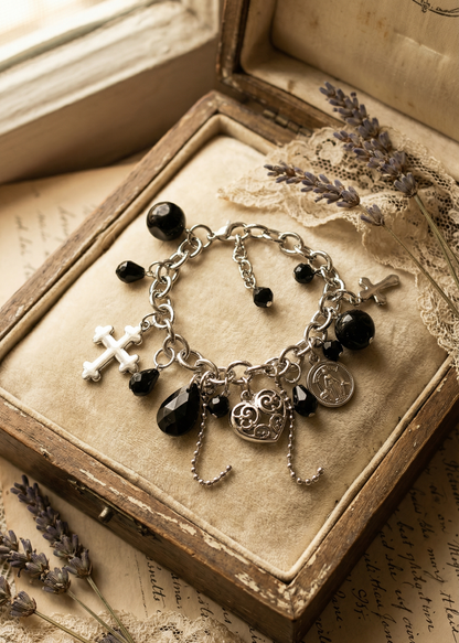 Gothic Armkettchen mit schwarzen Perlen, Kreuzen und Anhängern auf heller Schmuckschatulle.