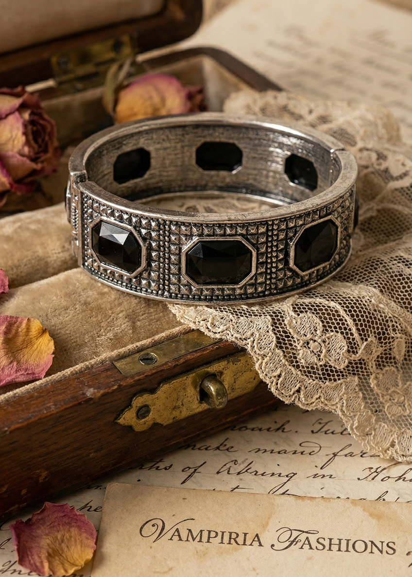 Barocke Armspange in Antik-Silber mit schwarzen facettierten Steinen auf Vintage-Holzuntergrund