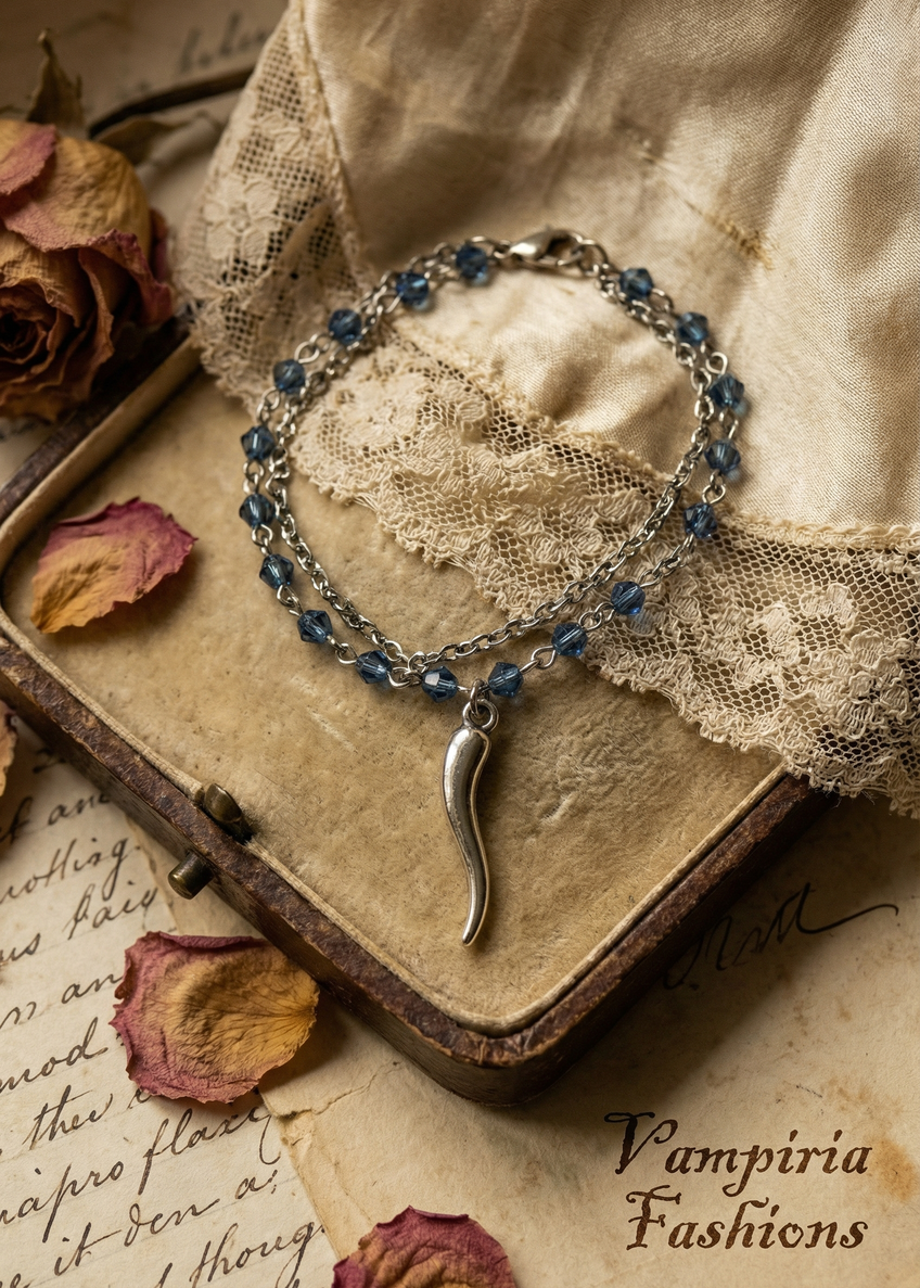 Filigranes Armkettchen mit blauen Perlen und geschwungenem Anhänger auf Vintage-Untergrund.