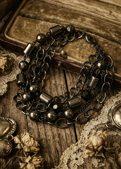 Mehrreihige schwarze Armkette mit facettierten Onyx-Perlen auf Holzuntergrund.