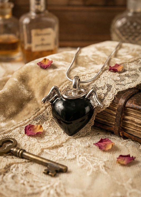 Schwarzer Herzanhänger mit Flügeln an Kette, dekoriert auf Spitze und Vintage-Unterlage