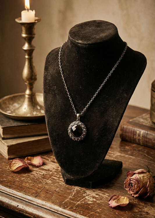 Gothic Kette mit ovalem schwarzem Medaillon auf schwarzer Schmuckbüste vor Vintage-Dekoration.