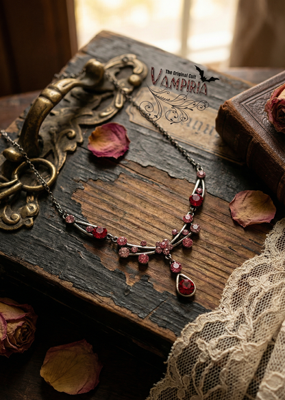 ampiria Gothic Collier mit pink-roten Kristallen auf rustikalem Holztisch mit Spitze und Rosenblättern.