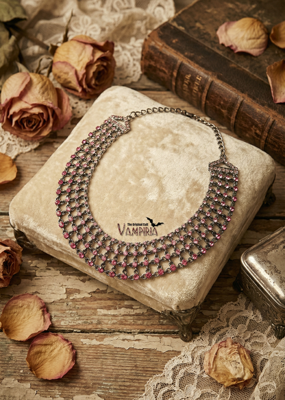 Mehrreihiges Collier mit pinken Strasssteinen auf hellem Samtkissen im Vintage-Setting.