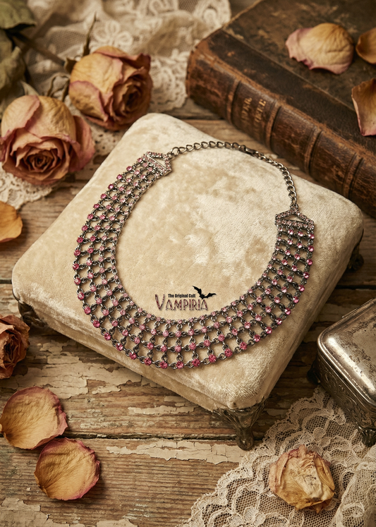 Mehrreihiges Collier mit pinken Strasssteinen auf hellem Samtkissen im Vintage-Setting.