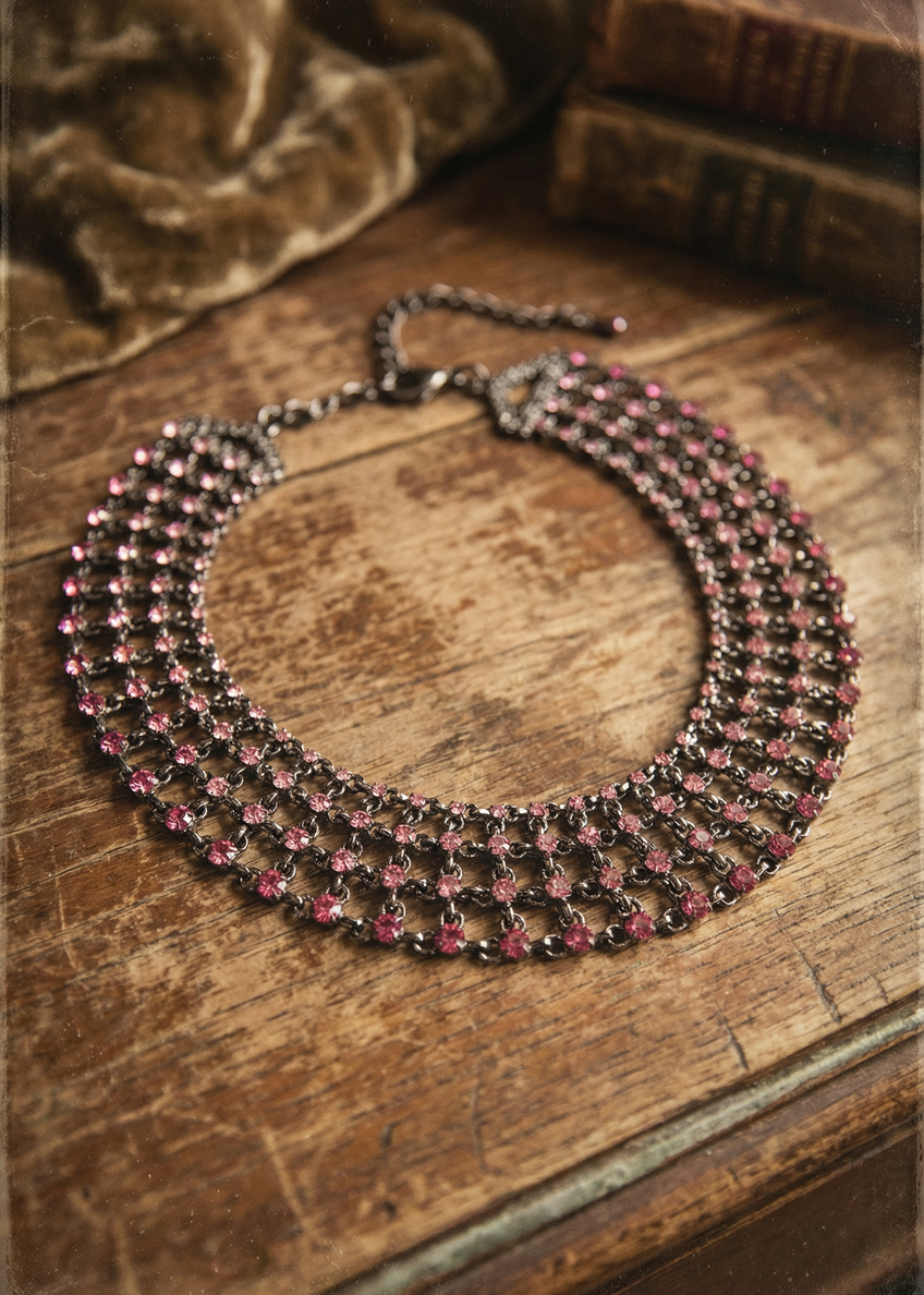 Collier mit pinken Strasssteinen flach auf Holztisch fotografiert, netzartige Struktur sichtbar.