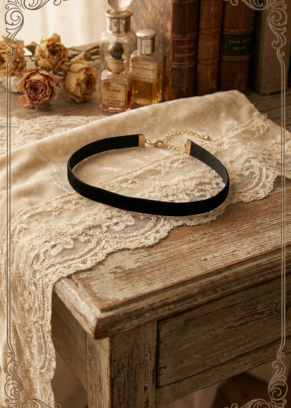 Schwarzes Samt-Halsband mit goldfarbenem Verlängerungskettchen auf vintage Tisch dekoriert.