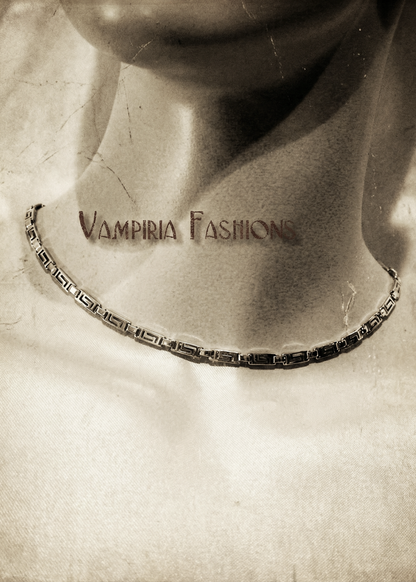 Silberfarbenes Metallcollier mit Greek-Key-Gliedern am Hals getragen, Nahaufnahme im Sepia-Stil.