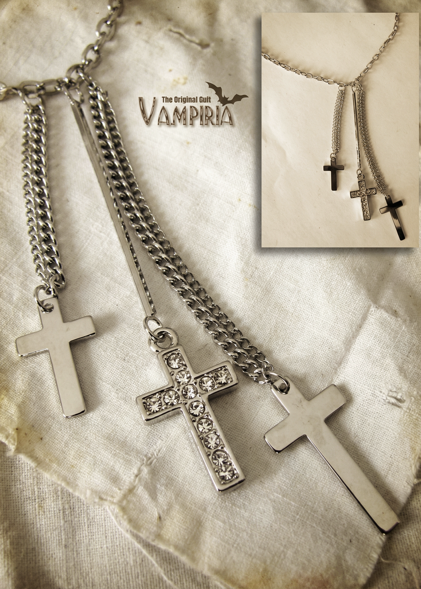 Nahaufnahme der Triple-Cross-Halskette auf hellem Stoff mit Einblendung des gesamten Schmucks im kleinen Bildausschnitt.