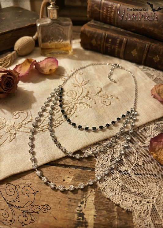 Mehrreihiges Crystal Collier mit klaren und schwarzen Steinen auf besticktem Stoff mit Spitze, Rosenblättern und Vintage-Dekoration.