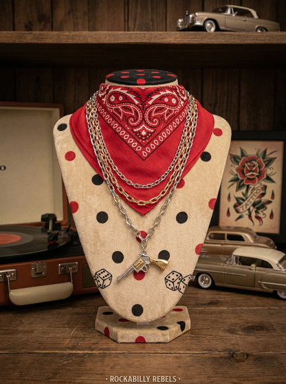 Mehrlagige Rockabilly-Kette mit Revolver-Anhänger auf Schmuckbüste mit rotem Bandana vor Retro-Dekoration.