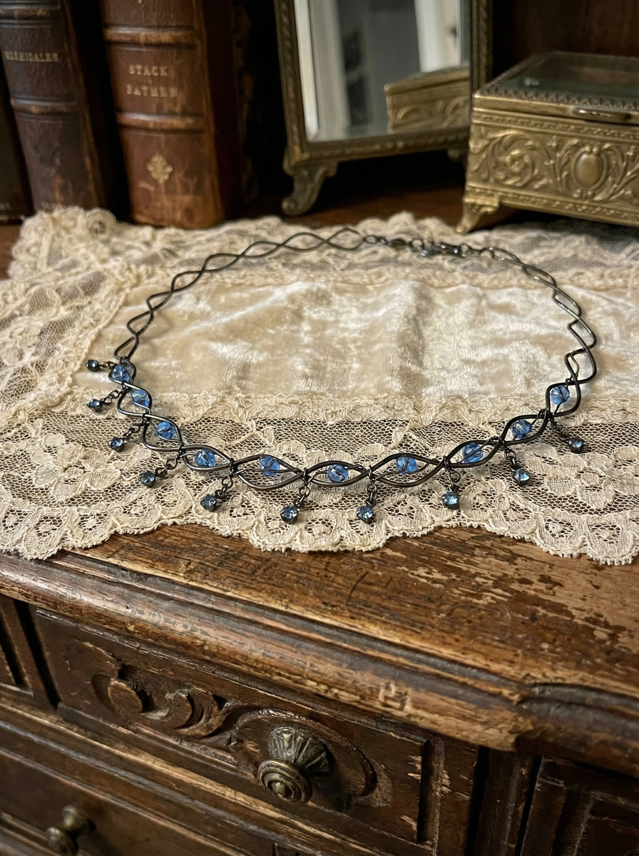 Collier ausgebreitet auf Spitzenstoff auf einem Holzmöbel im Vintage-Stil.