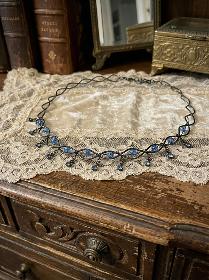Collier ausgebreitet auf Spitzenstoff auf einem Holzmöbel im Vintage-Stil.