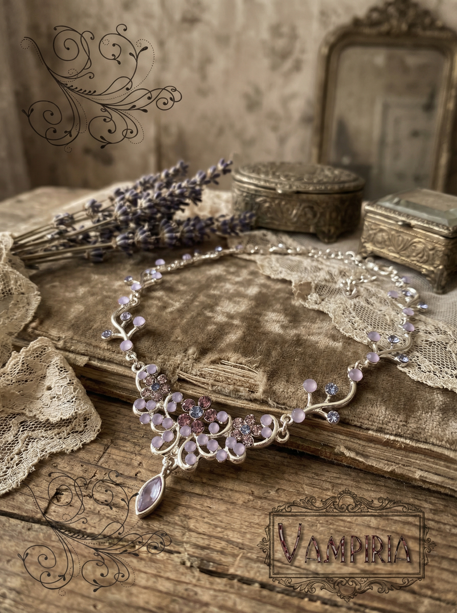 Florales Collier in Silberoptik mit lilafarbenen Steinen auf altem Buch mit Spitze und Lavendel; unten rechts ist der Schriftzug „Vampiria“ zu sehen.