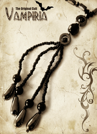 Detailaufnahme des unteren Y-Anhängers mit drei schwarzen tropfenförmigen Hämatit-Perlen, kleinen schwarzen Perlen und dunklen Metallelementen auf hellem Hintergrund.