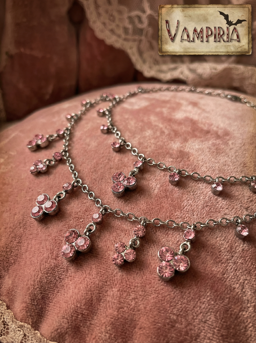 Nahaufnahme eines pinken Crystal Colliers mit rosa Kristallanhängern auf rosafarbenem Samtstoff.