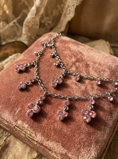 Pink Crystal Collier mit rosa Kristallanhängern auf rosafarbenem Samtkissen in Nahaufnahme.