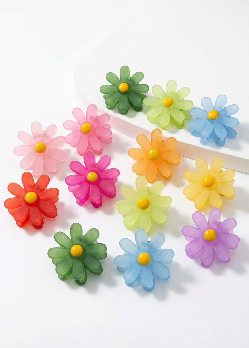 Farbig gemischte Mini-Haarklammern in Blumenform mit gelber Mitte auf weißem Hintergrund, teilweise einzeln angeordnet.
