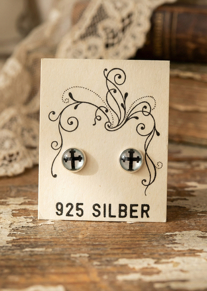 Runde Ohrstecker mit schwarzem Kreuz-Motiv aus 925 Silber auf Schmuckkarte.