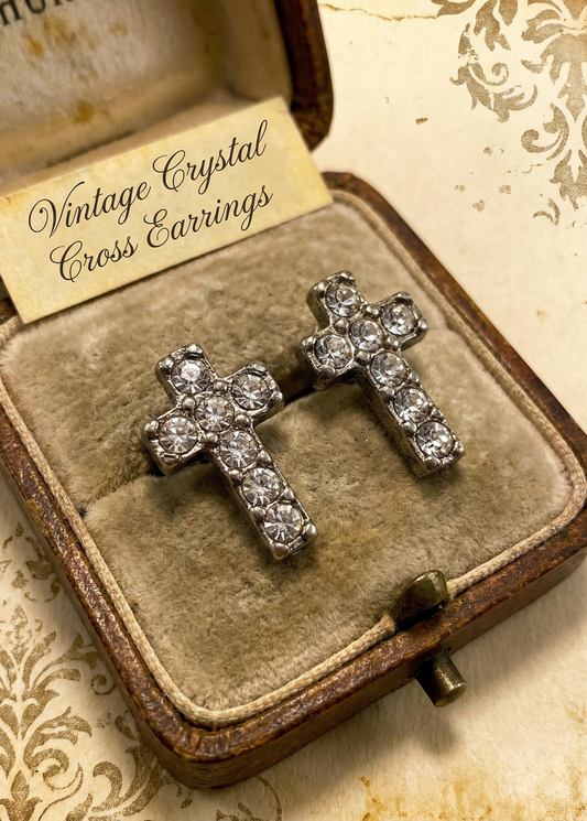 Zwei silberfarbene Mini-Ohrstecker in Kreuzform mit klaren Strasssteinen in einer geöffneten braunen Schmuckschatulle auf hellem Untergrund; im Deckel steht „Vintage Crystal Cross Earrings“.