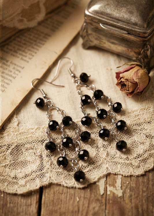 Barocke Vintage Ohrhänger mit schwarzen Perlen liegen auf Spitze und Holzuntergrund
